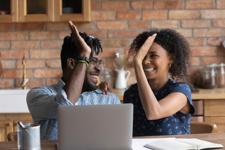 Two smiling people high-fiving to success